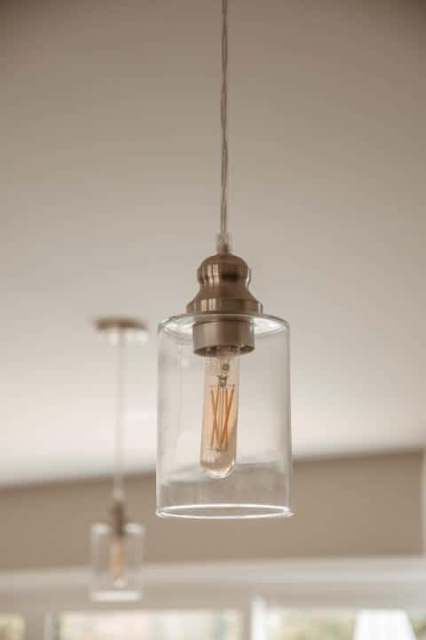 A pendant light with a clear glass shade is hanging from the ceiling in a kitchen.