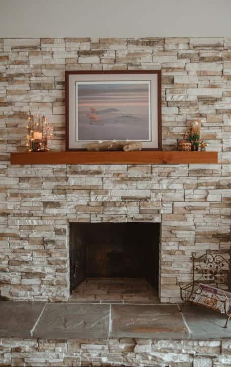 A brick fireplace with a picture on the mantle.