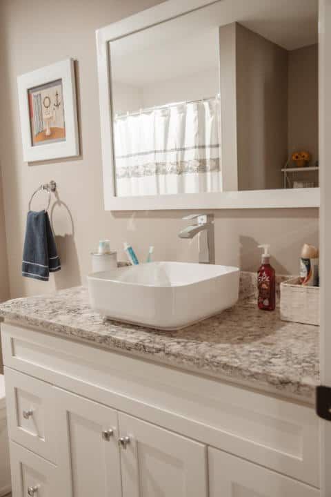 A bathroom with a sink , mirror and cabinets.
