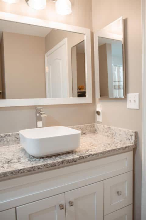 A bathroom with a sink , mirror , and cabinets.