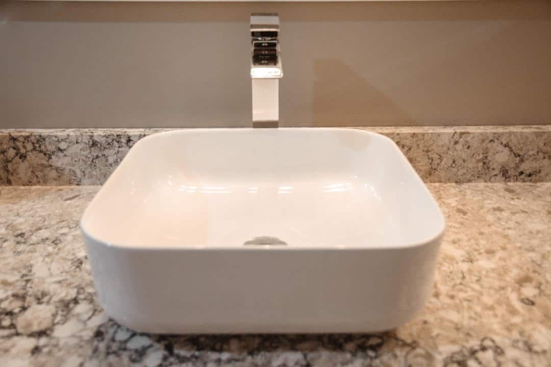 A bathroom sink is sitting on top of a granite counter top.