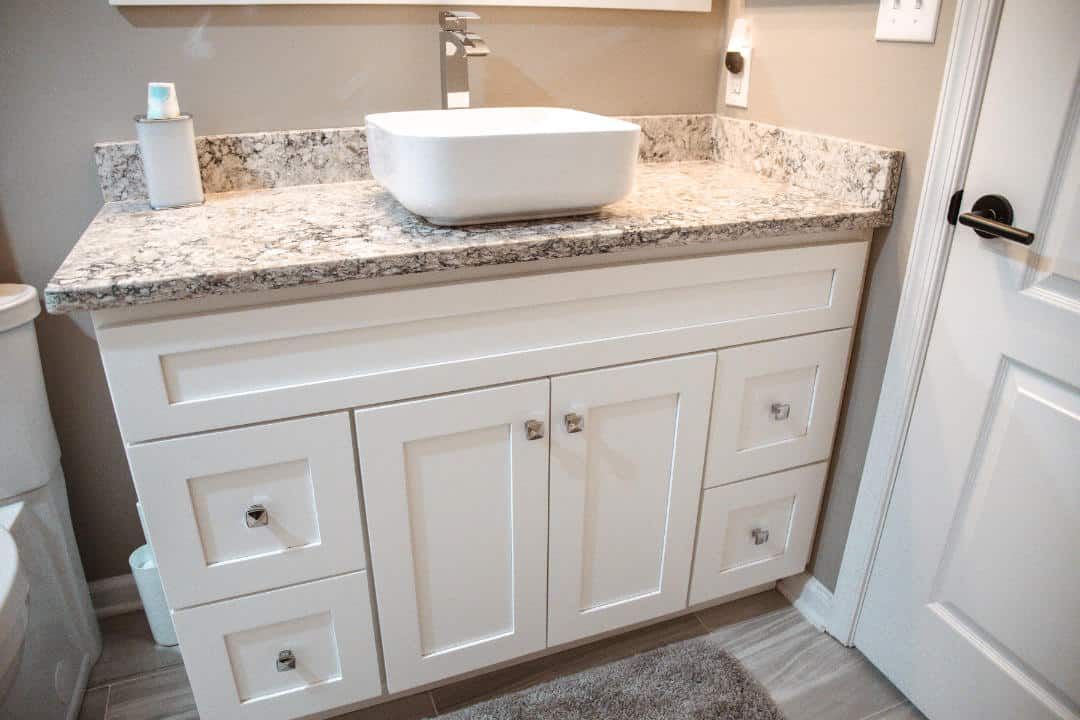 A bathroom vanity with a sink and granite counter top.