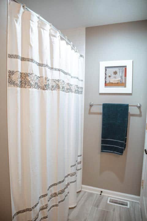 A bathroom with a shower curtain and a towel rack.