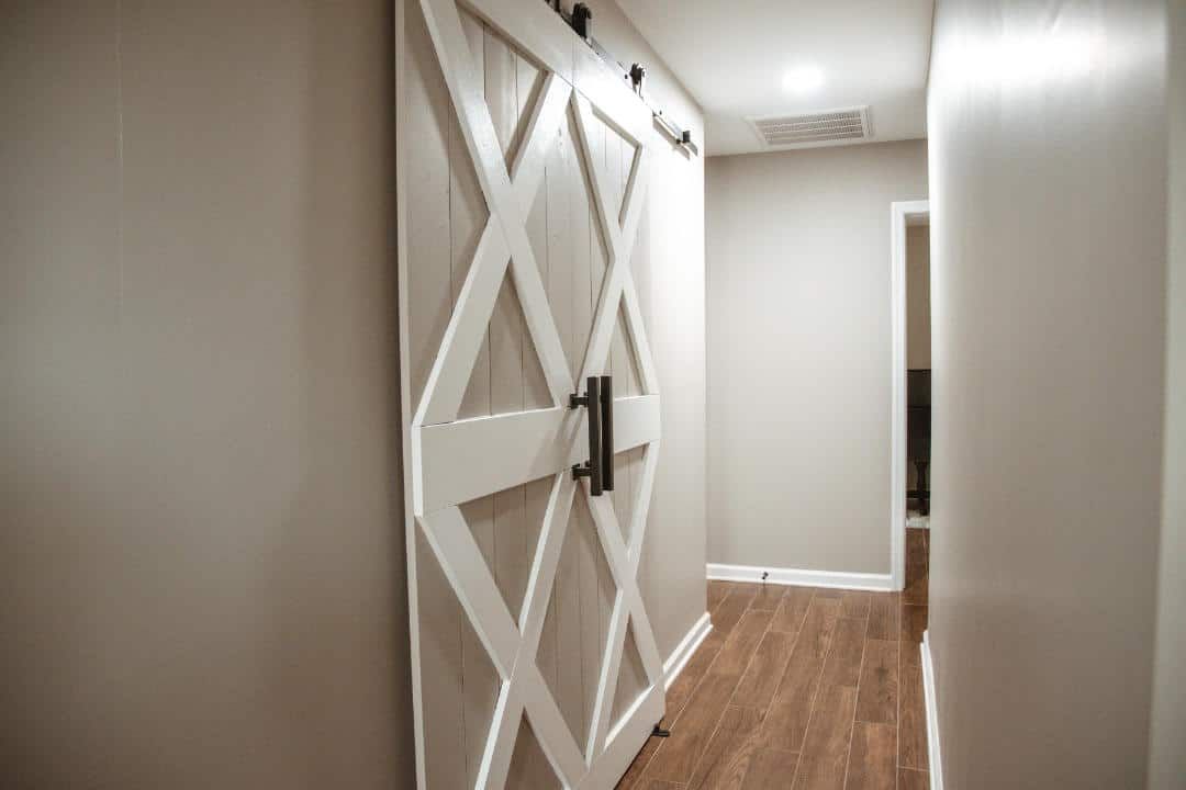 A hallway with a sliding barn door on the wall.