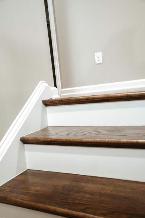A close up of a set of wooden stairs with white trim.