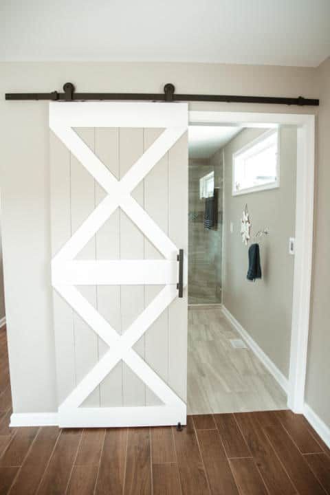 A white sliding barn door is open to a bathroom.