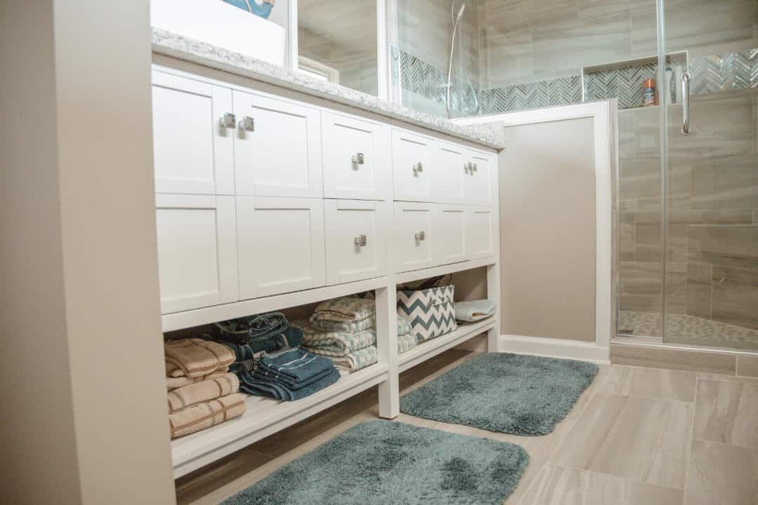 A bathroom with two sinks , a mirror , and a walk in shower.