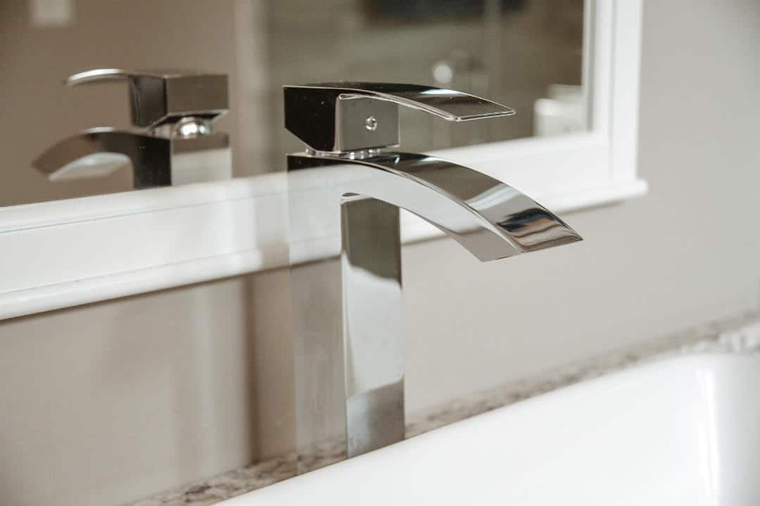 A bathroom sink with a chrome faucet and a mirror.