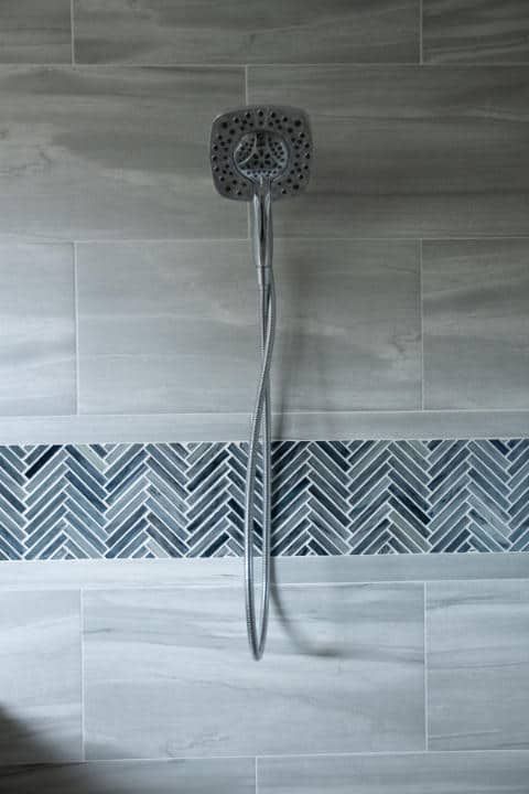 A shower head is hanging from a tiled wall in a bathroom.