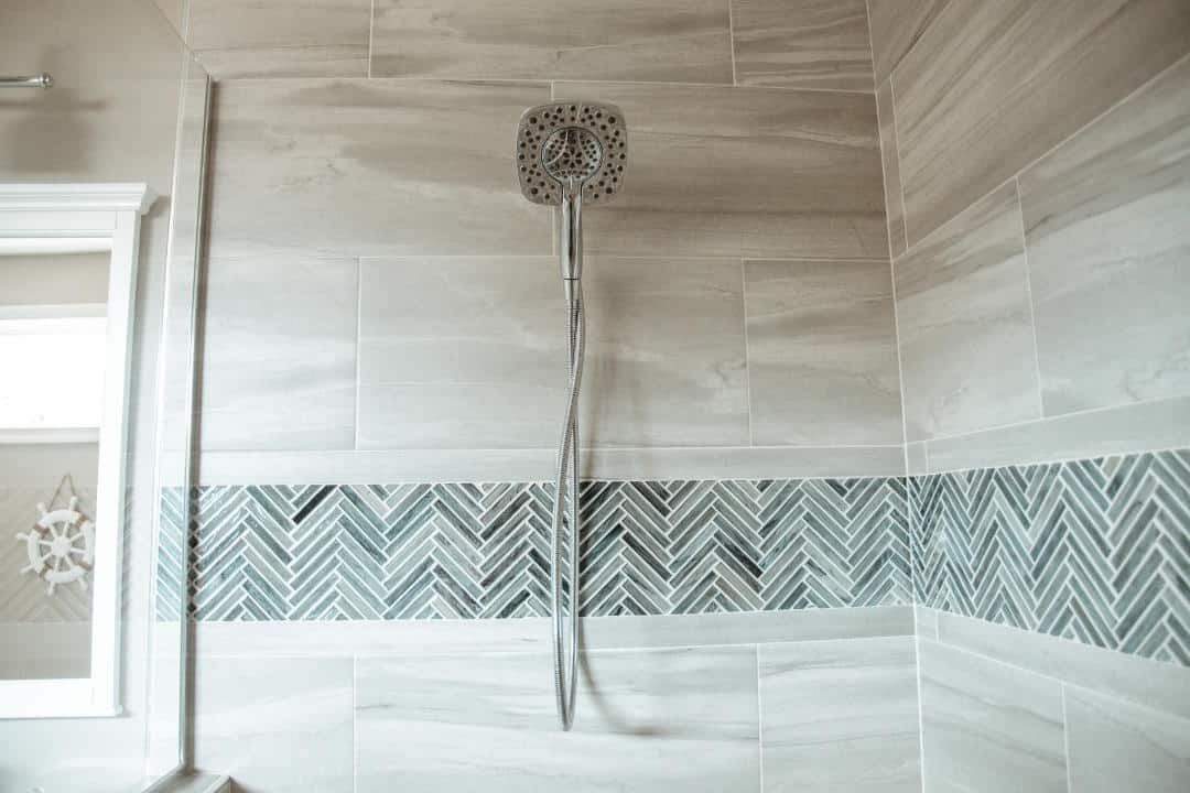 A shower head is hanging from the ceiling in a bathroom.