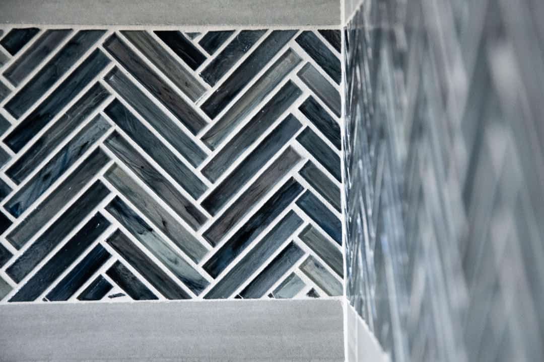 A close up of a shower tile with a herringbone pattern.