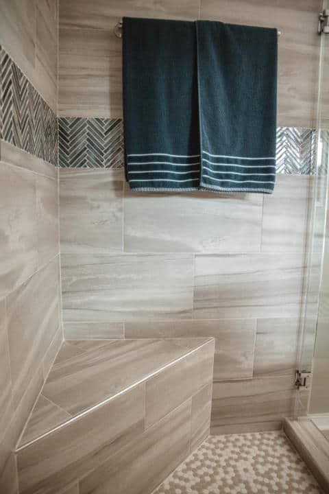 A bathroom with a bench and two towels hanging on the wall.