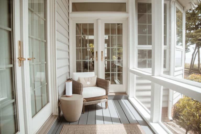 A screened in porch with a chair and a table.