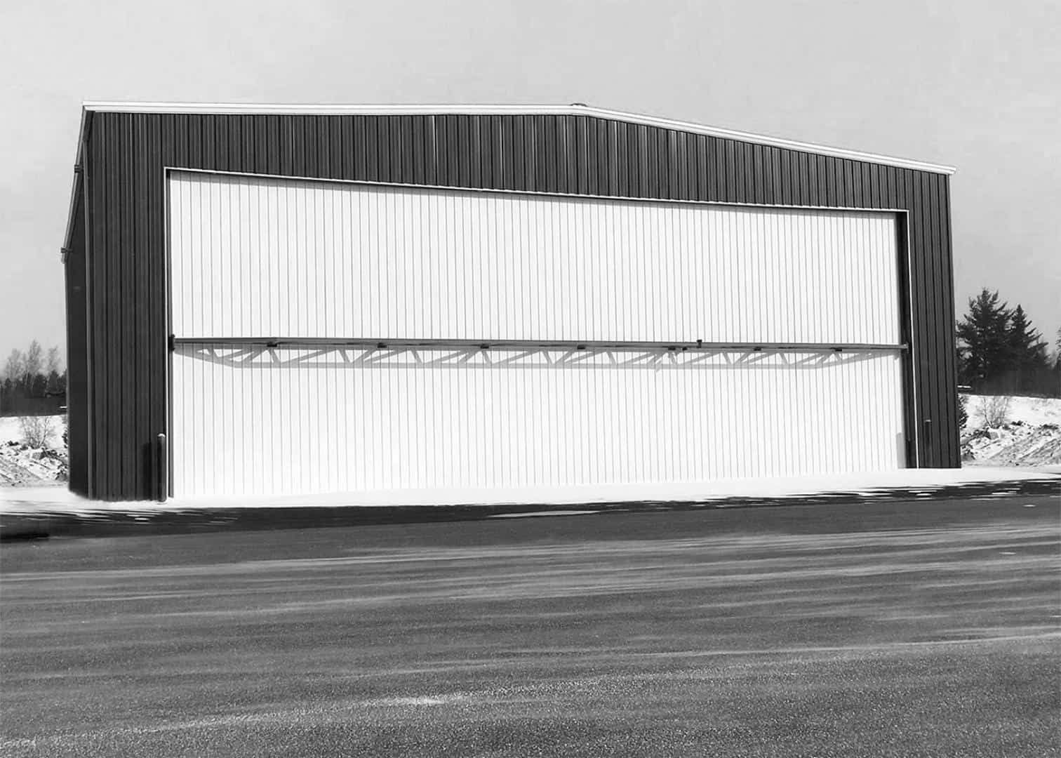 A black and white photo of a hangar with its doors open.