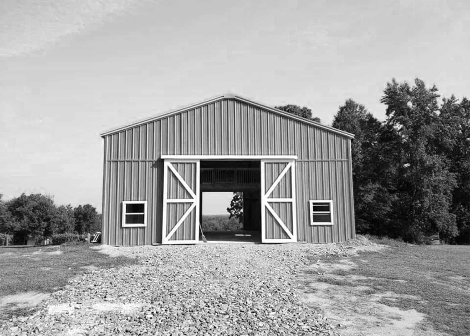 A black and white photo of a barn with the doors open