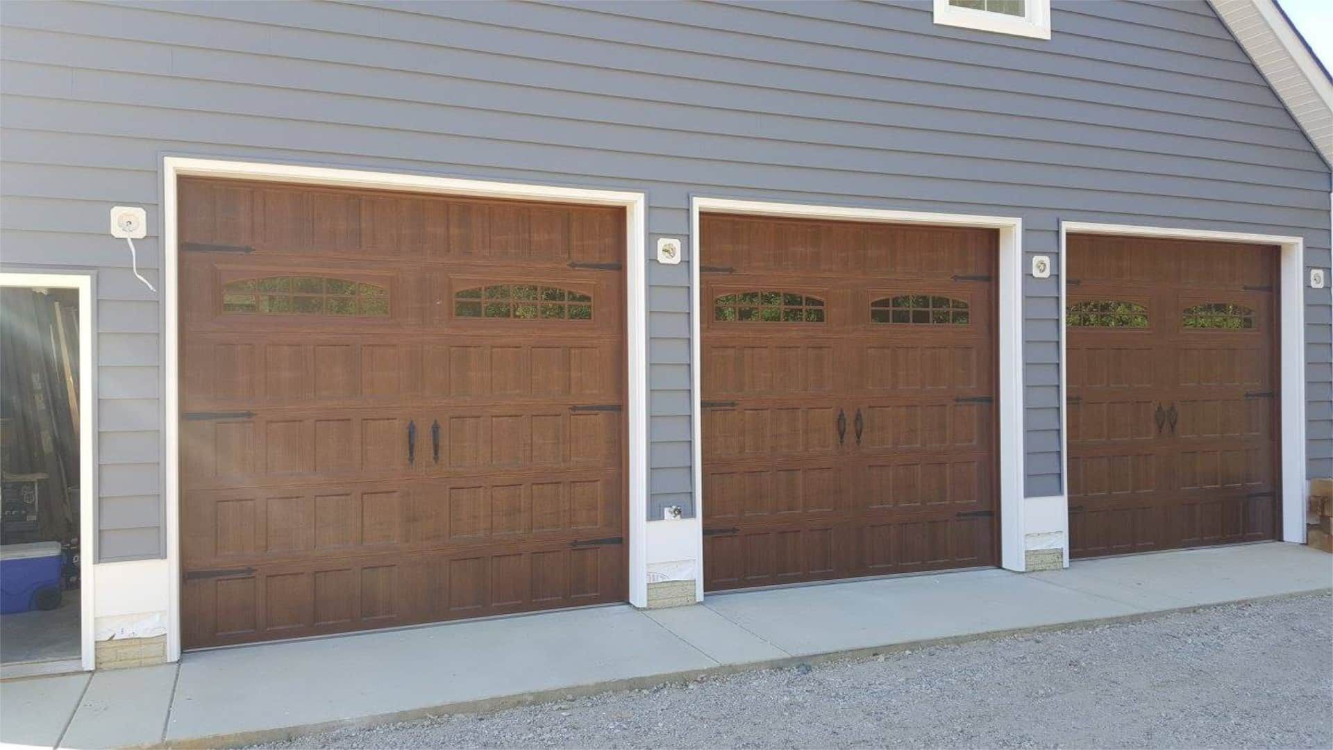 There are three garage doors on the side of a building.