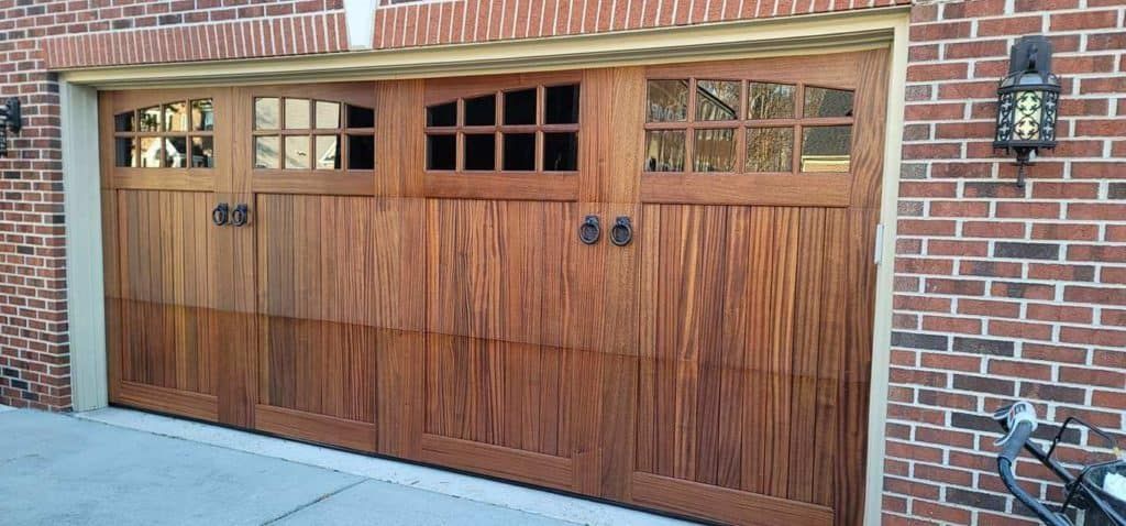 A wooden garage door with a brick wall behind it