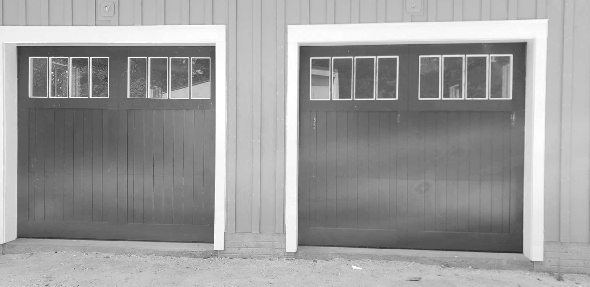 A black and white photo of two garage doors on a building.