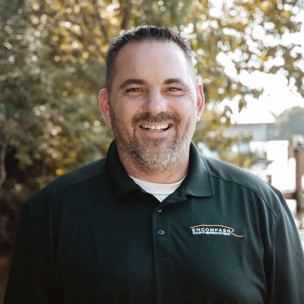 A man with a beard is smiling for the camera while wearing a black shirt.