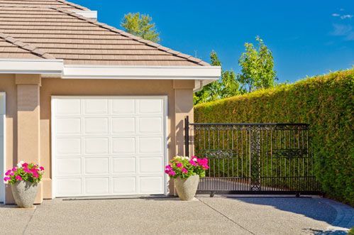 A house with a white garage door and flowers in front of it.
