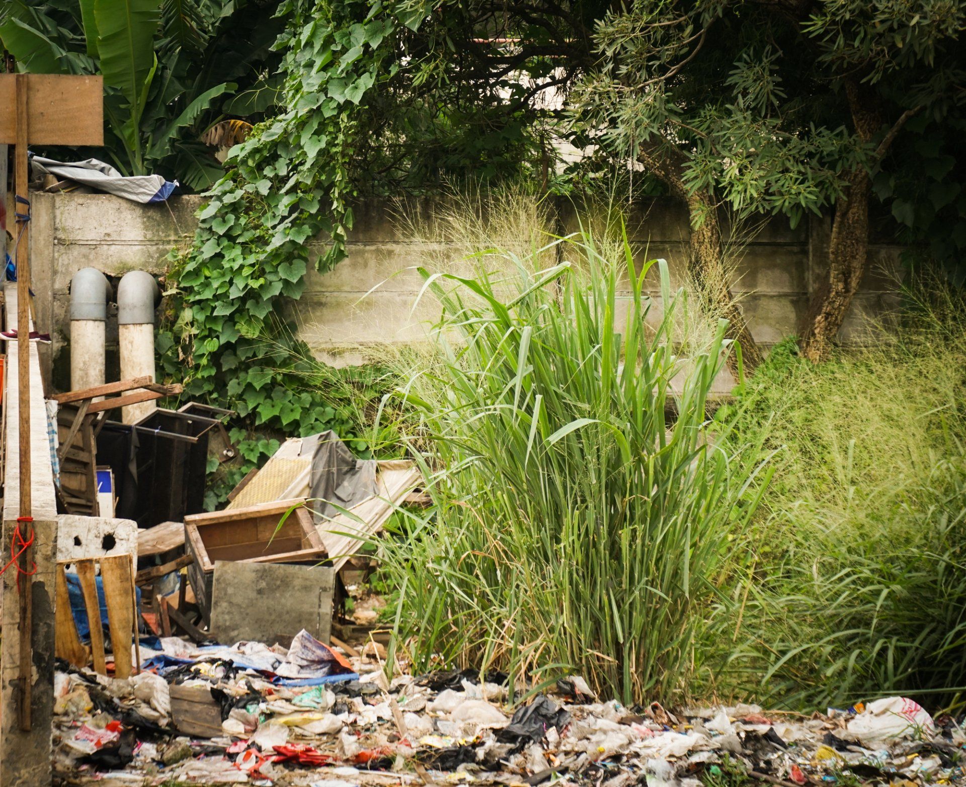 A pile of trash is sitting in the grass next to a wall.