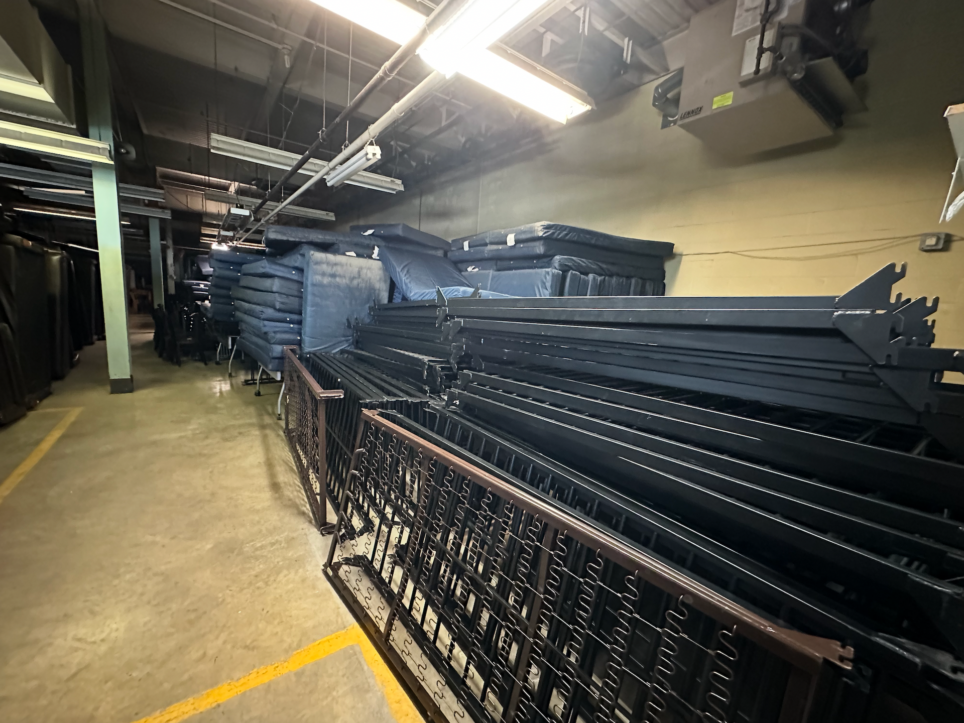 Three people carefully moving a piano, wrapped in plastic, in a room with hardwood floors.