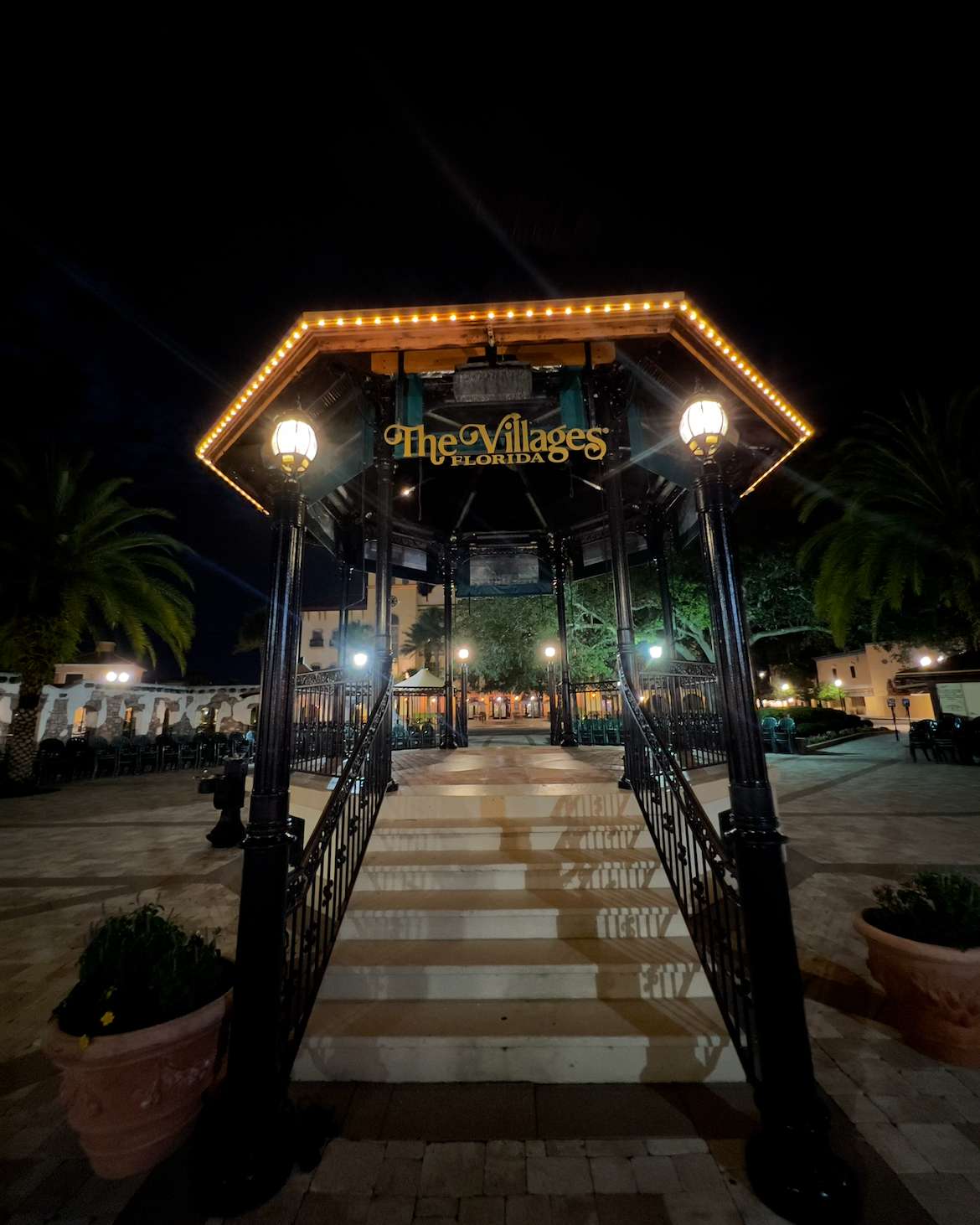 Two people in blue coveralls installing a washing machine in a bathroom with a hand truck.
