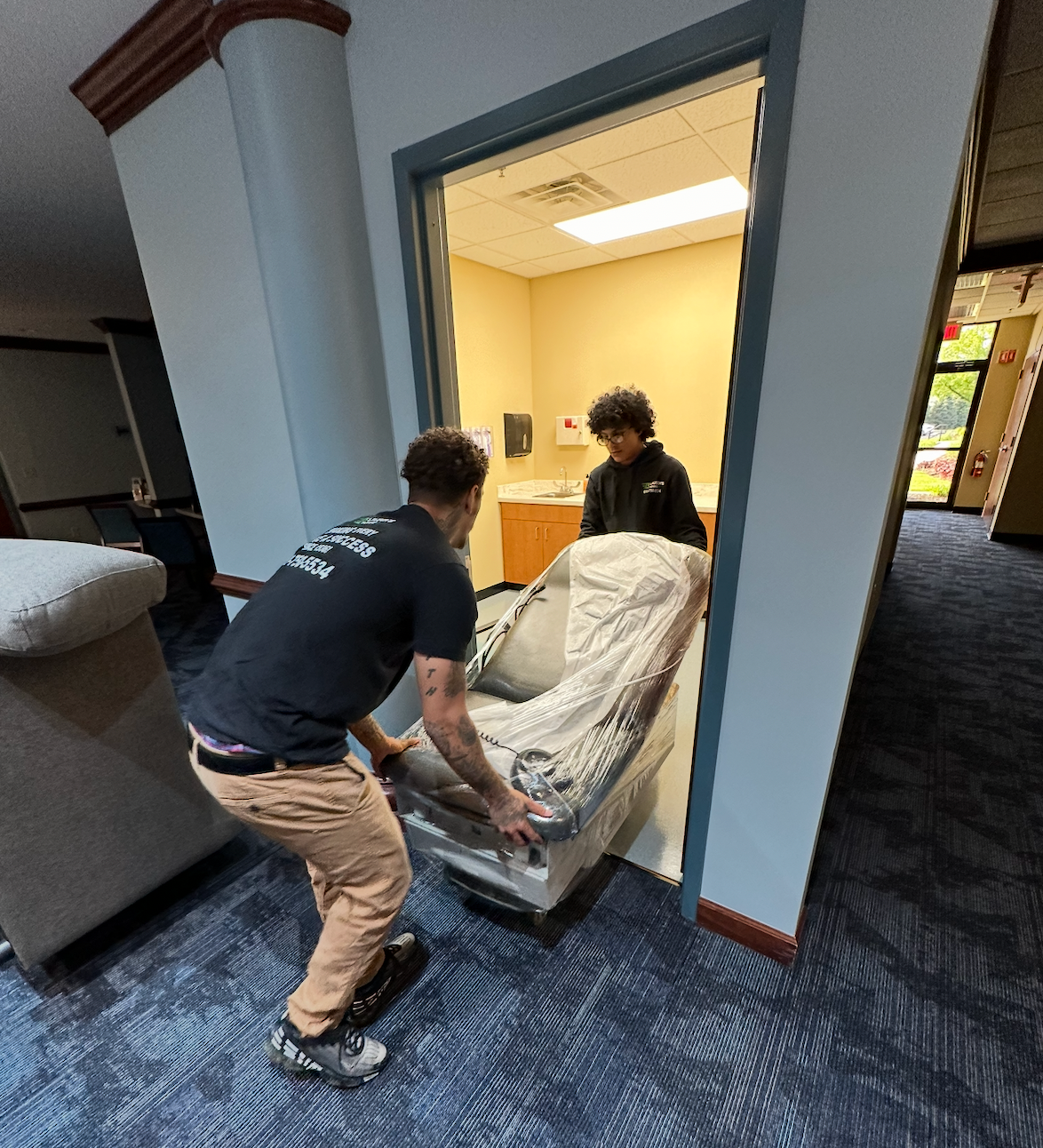 Storage units with open door showing stacked boxes, numbers 25 and 26 visible, blue sky.