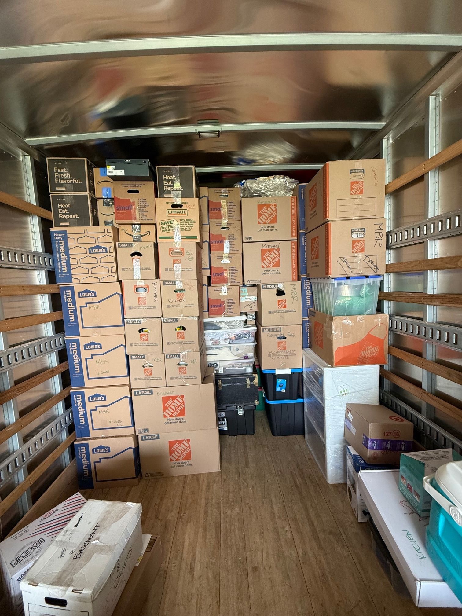 Boxes stacked inside a moving truck, full of items.