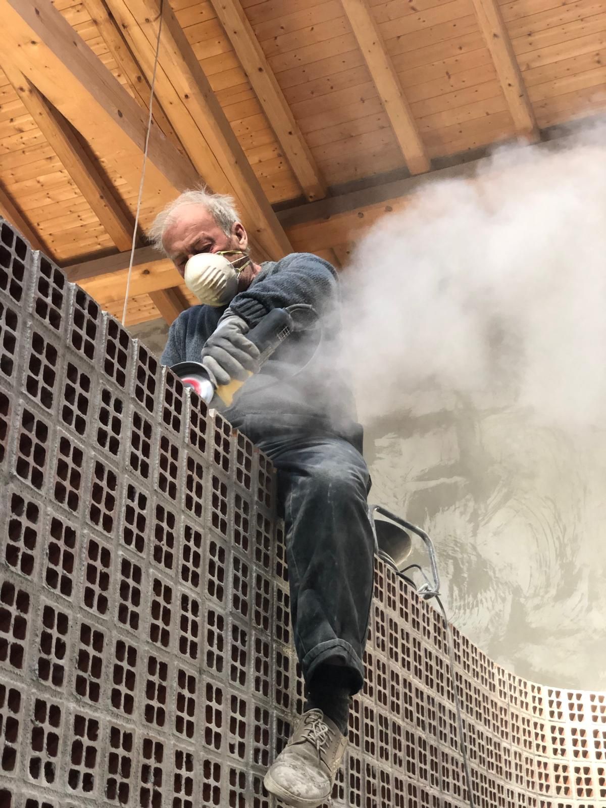 Cucina moderna con mobili grigi, ripiani in marmo e tre lampade a sospensione.