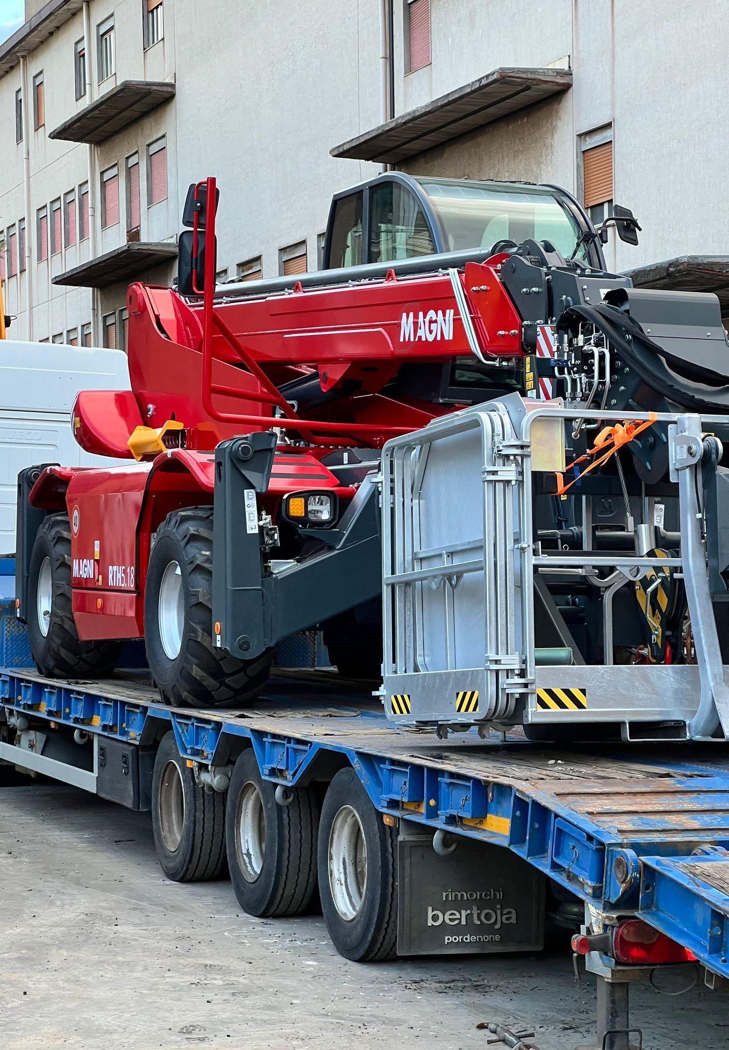 Cantiere con una gru alta sopra le tegole rosse in una giornata di sole.