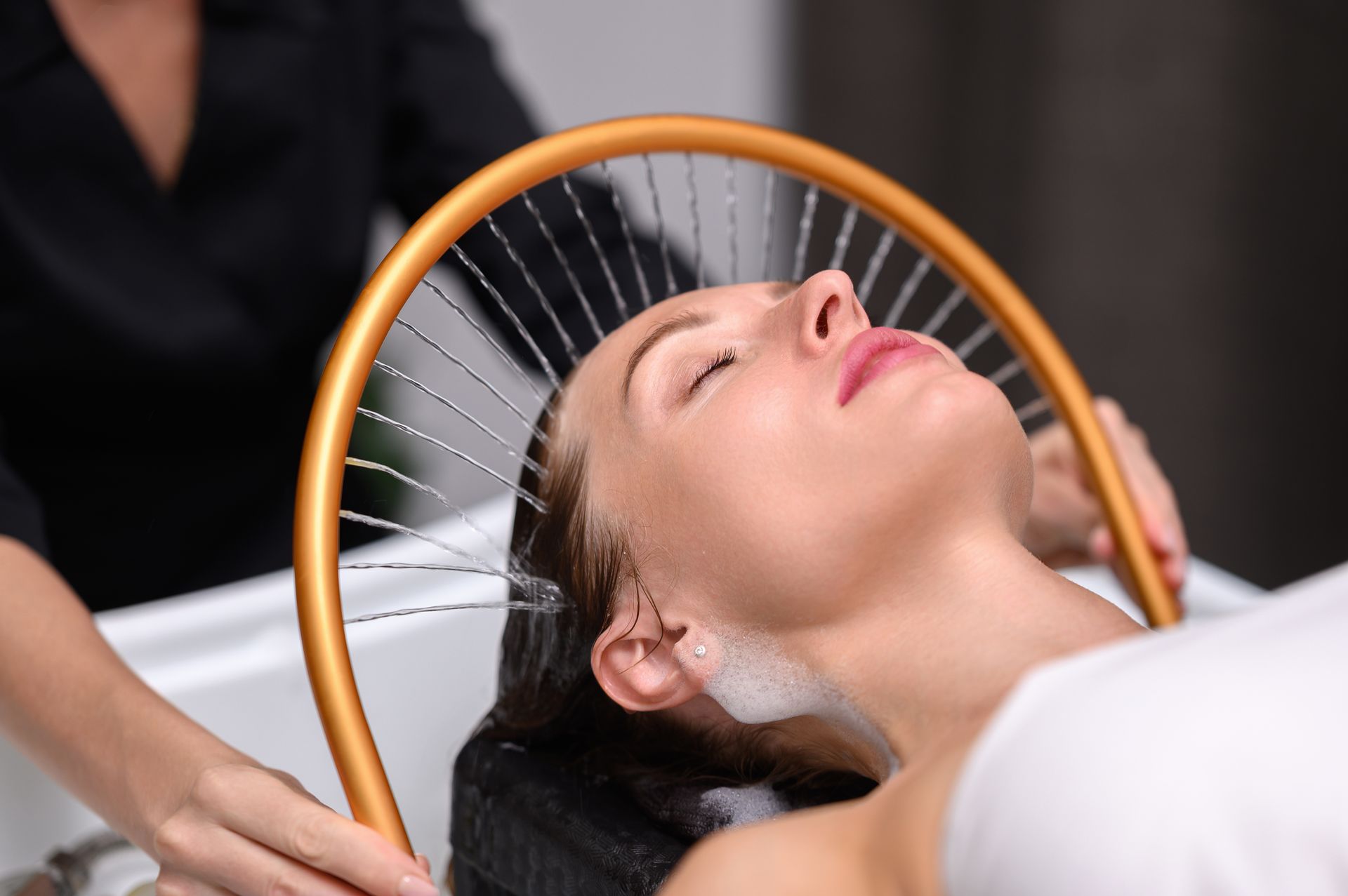 Spa massage with woman lying on towel, relaxing while therapist massages her head in a warm room