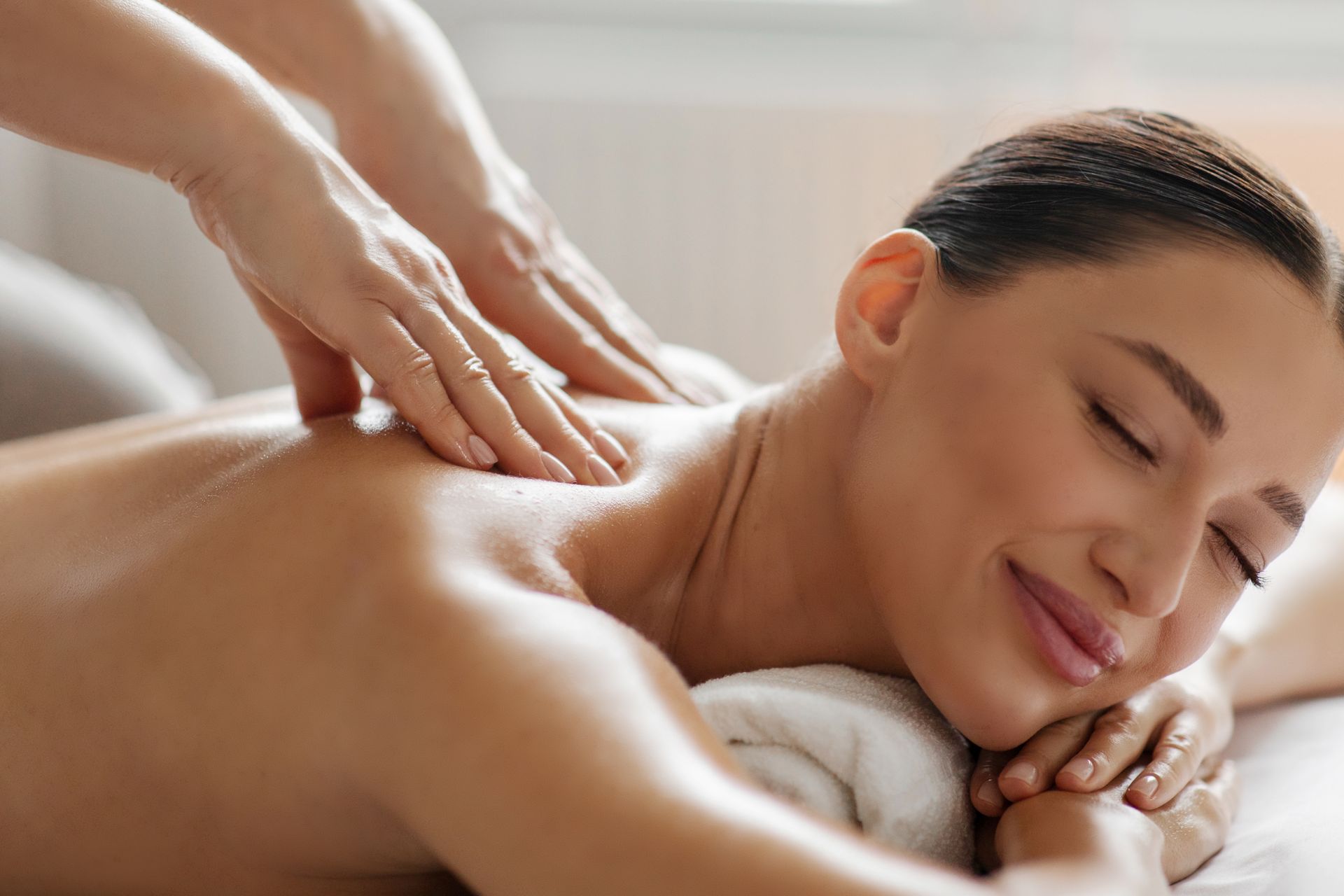 Person receiving a relaxing back massage on a spa table, eyes closed and smiling