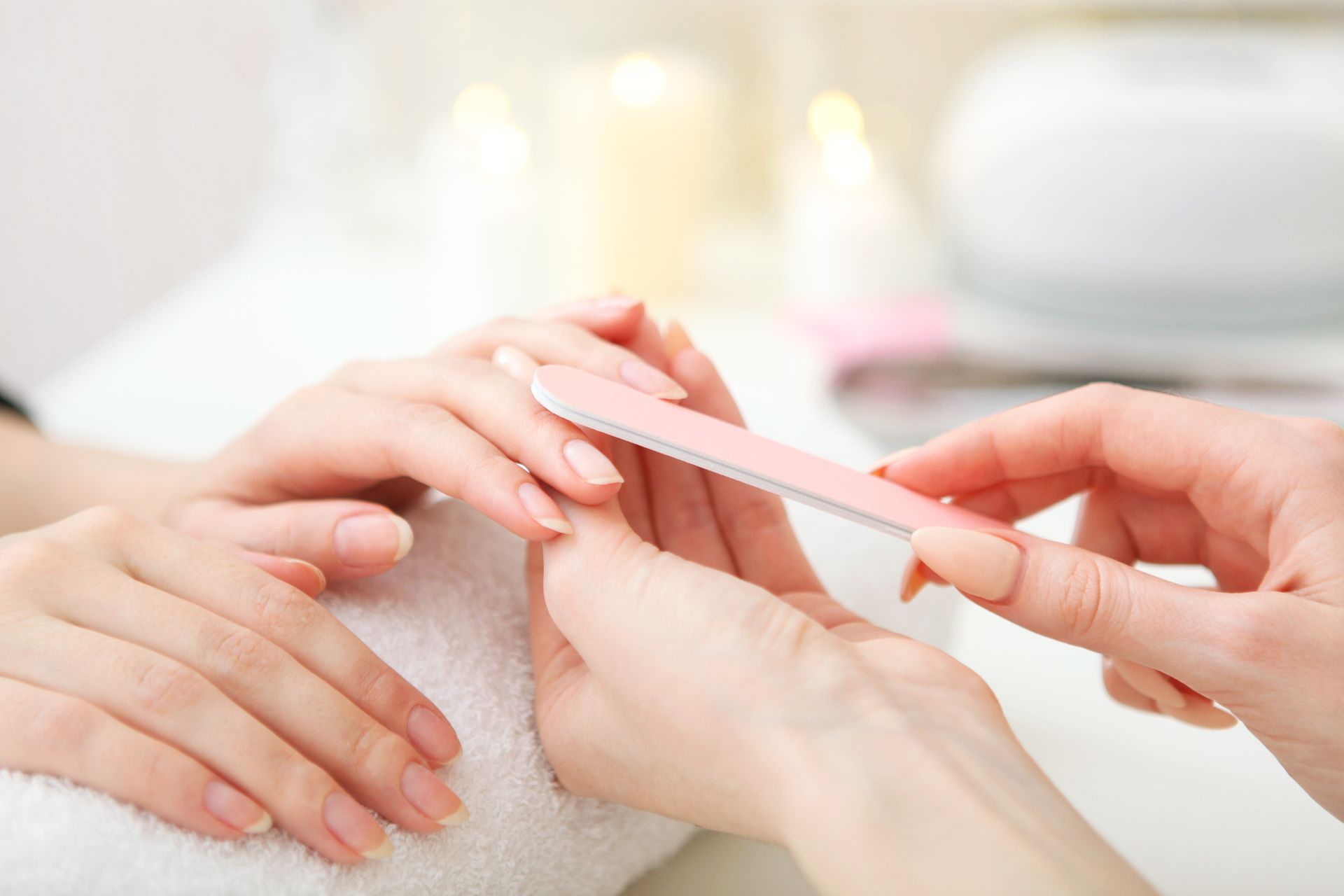 Hands getting a manicure with a nail file in a soft, bright spa setting