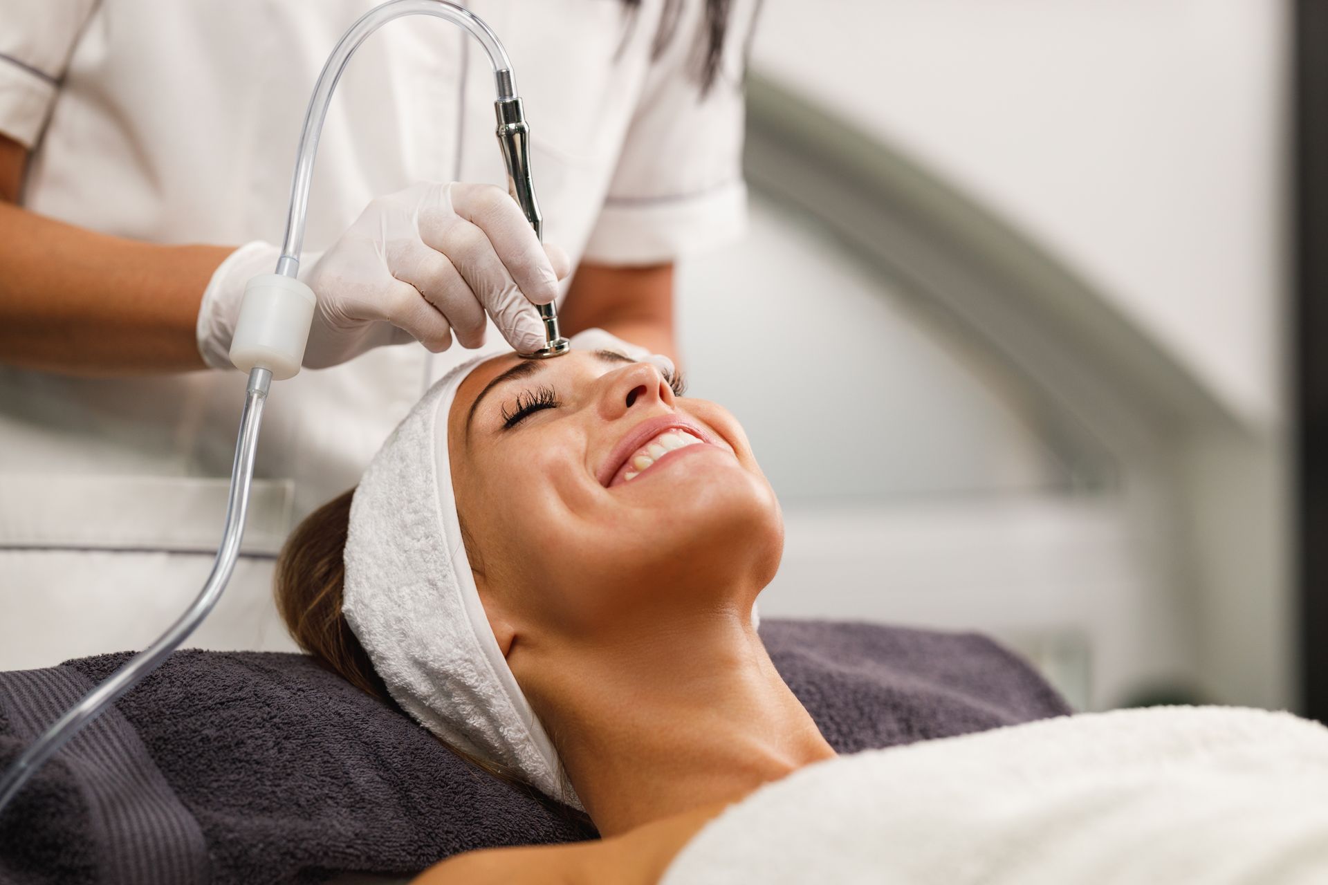 Woman receiving a facial treatment while reclining with a towel headband in a spa setting