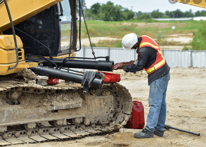 A construction worker is working on a bulldozer on a construction site.