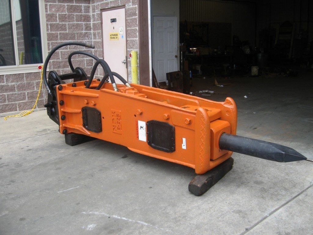 An excavator with a hydraulic hammer attached to it