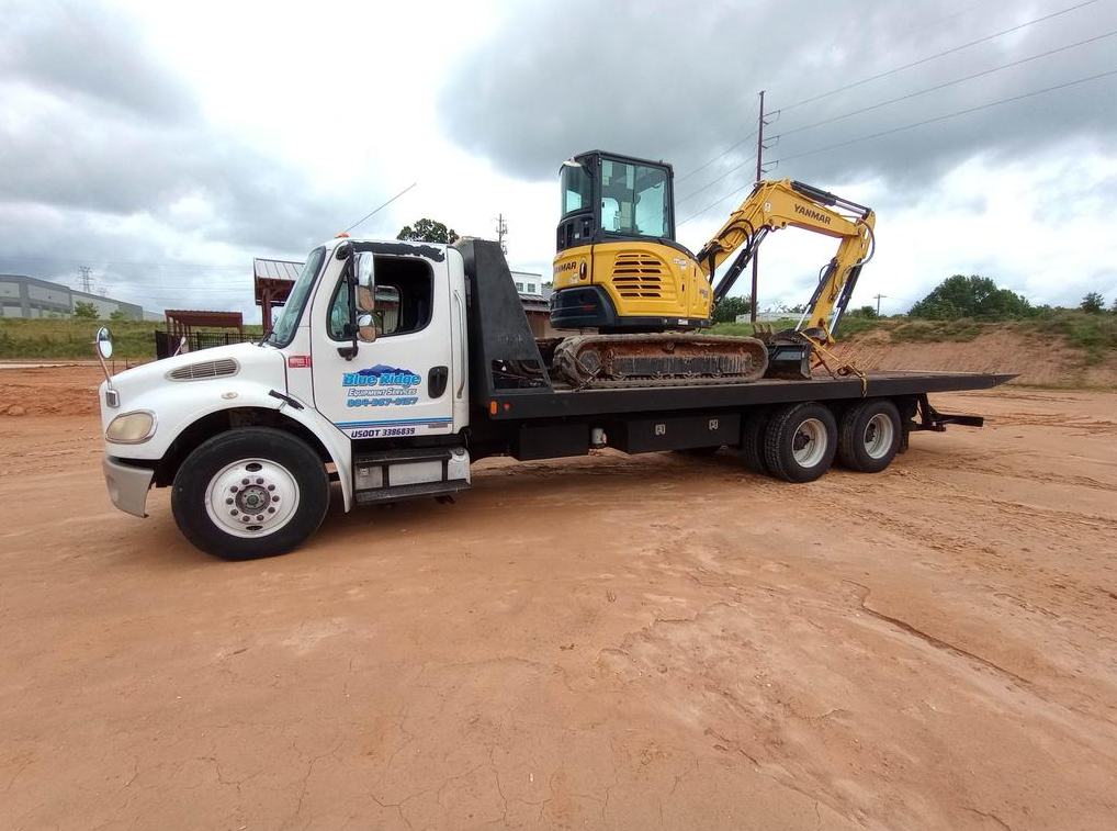 A flatbed tow truck is parked in a parking lot.