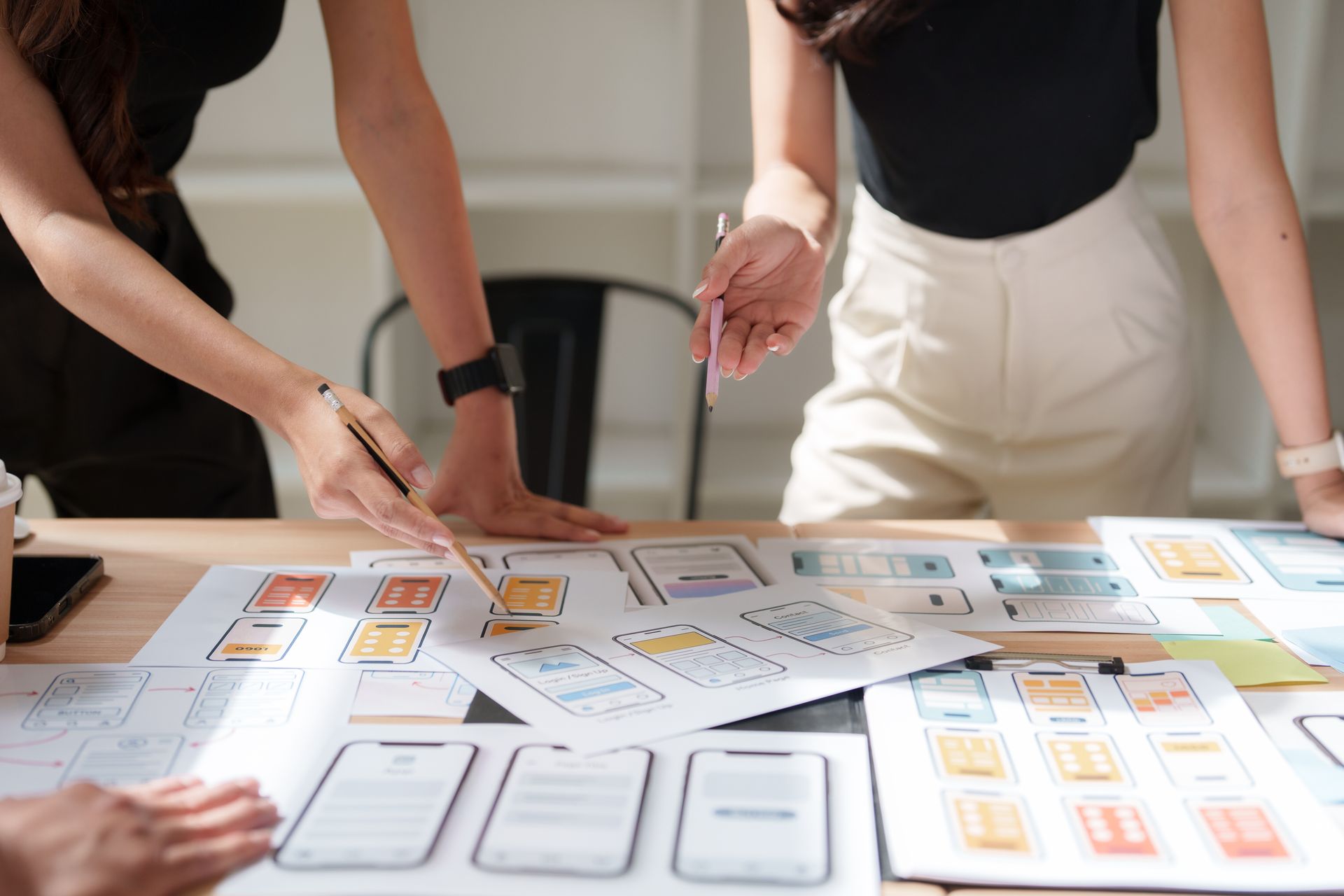 Two people designing a website layout on a whiteboard, labeling sections like logo, banner, and content with pixel dimensions.