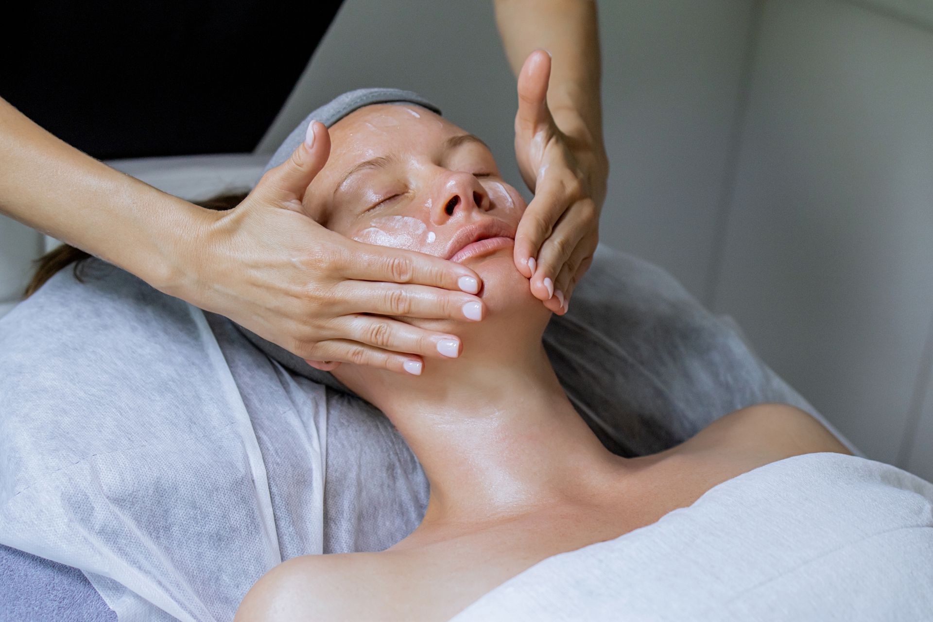 Close-up of a person receiving a facial skin treatment with a handheld device and gloved hand