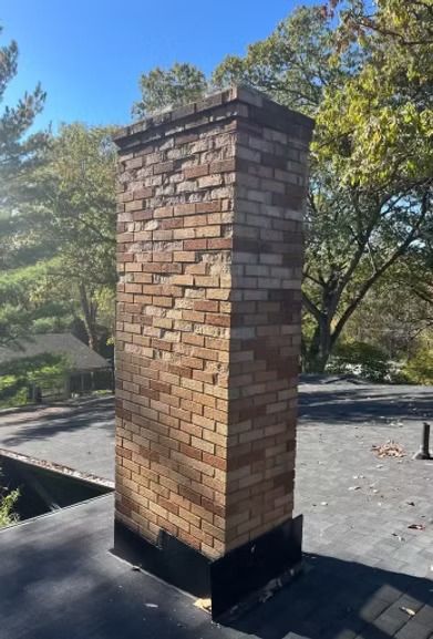 A brick chimney is sitting on top of a roof. A brick chimney is sitting on top of a roof.