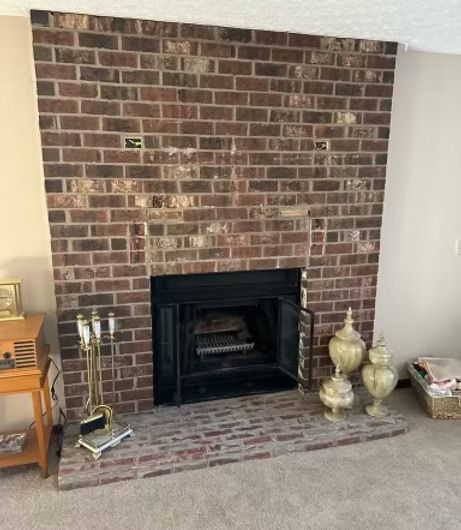 A living room with a brick fireplace and two vases on the floor. A living room with a brick fireplace and two vases on the floor.
