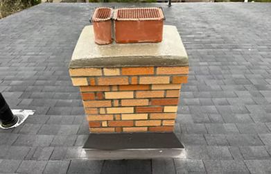 A brick chimney is sitting on top of a roof. A brick chimney is sitting on top of a roof.