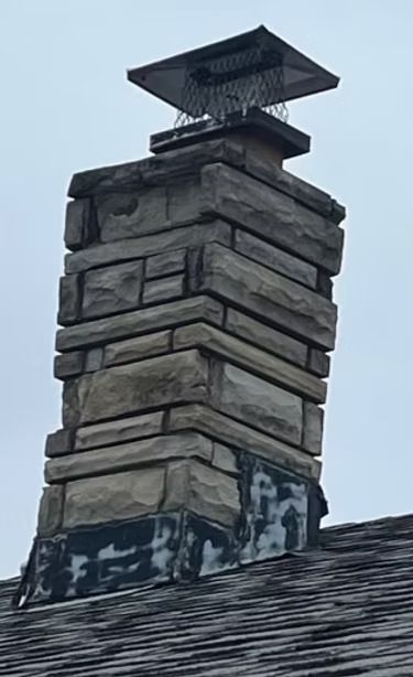 A stone chimney is sitting on top of a roof. A stone chimney is sitting on top of a roof.