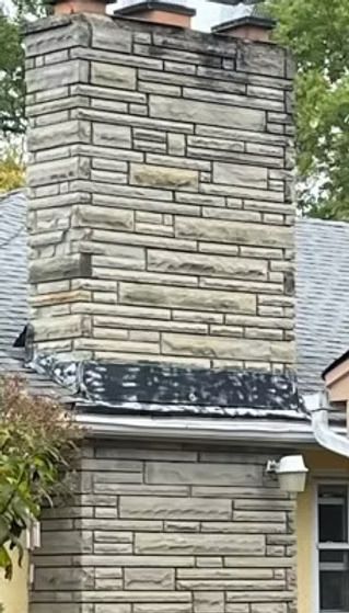 A brick chimney on the side of a house with a roof. A brick chimney on the side of a house with a roof.