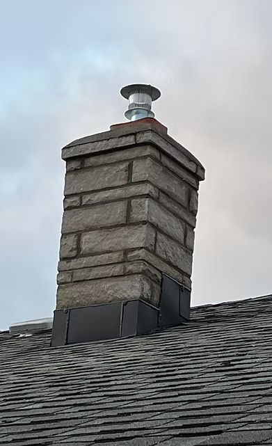 A brick chimney is sitting on top of a roof. A brick chimney is sitting on top of a roof.