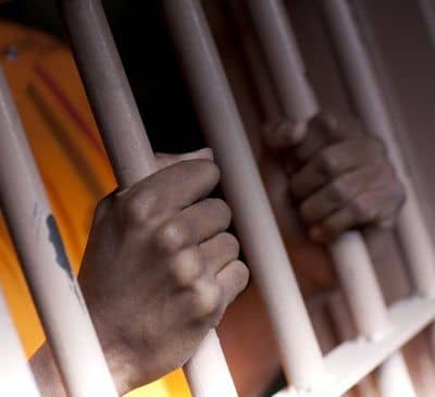 Hands grasping prison bars