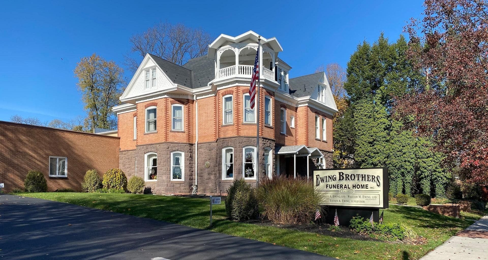 Brick building with a white tower, brown sign: Long Funeral Home. Sunny day with trees and lawn.