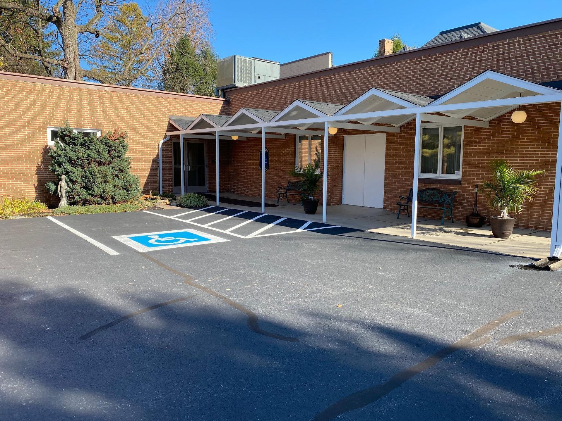 Exterior view of a brick building with a covered entrance, a handicap parking space visible.