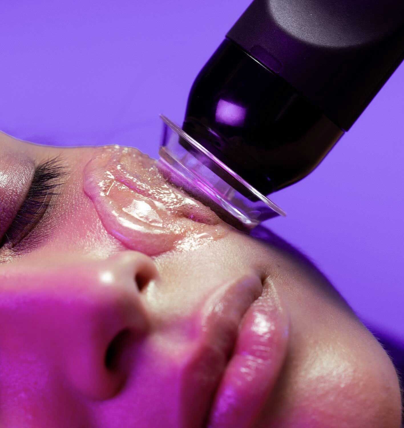 A woman is getting a facial treatment with a machine on her face.